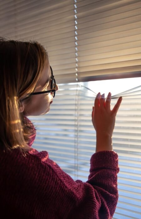 woman-looks-through-blinds-early-morning-sunlight_169016-17901